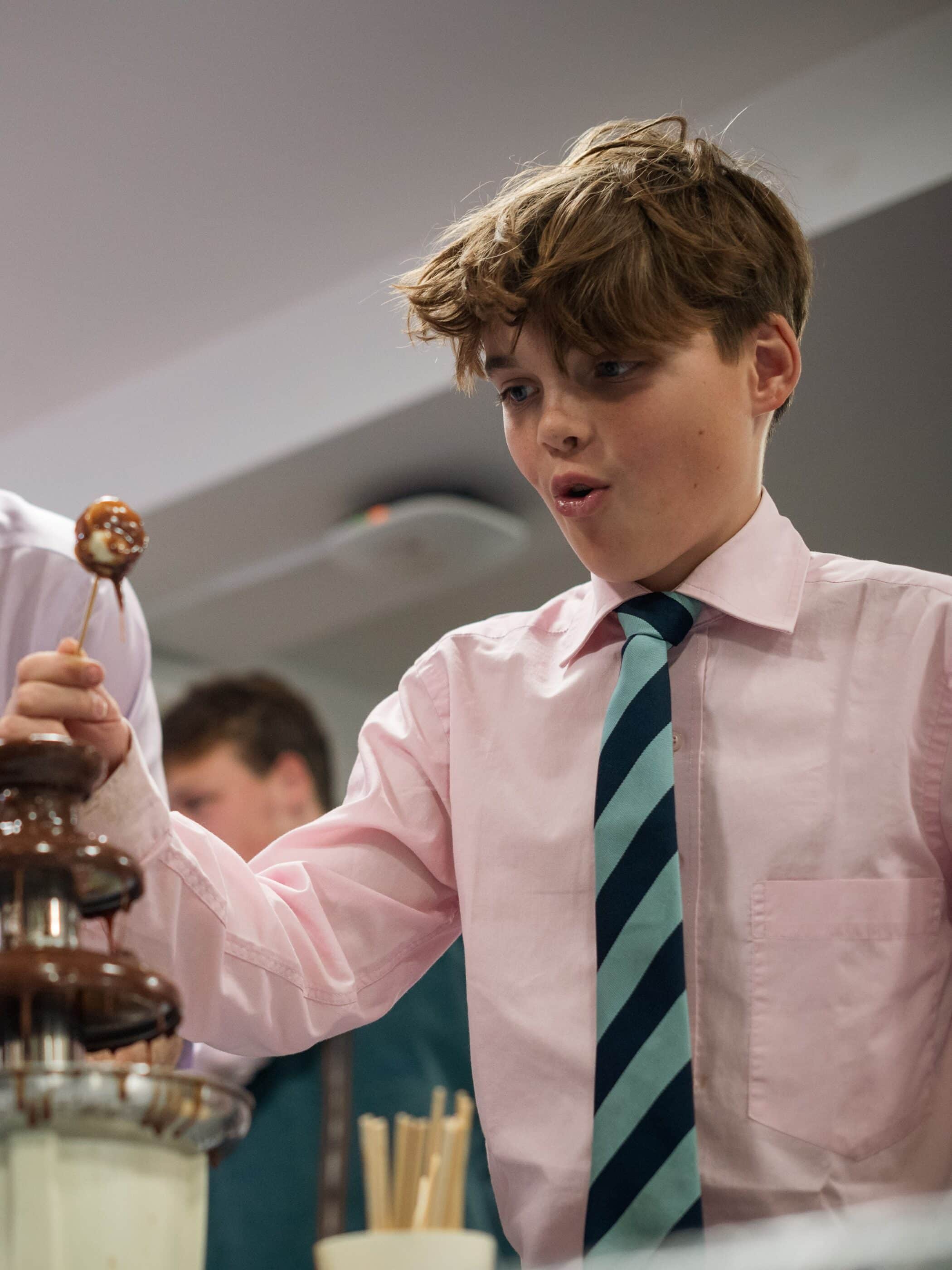 Boy sat eating and drinking with his friends in shirt and tie