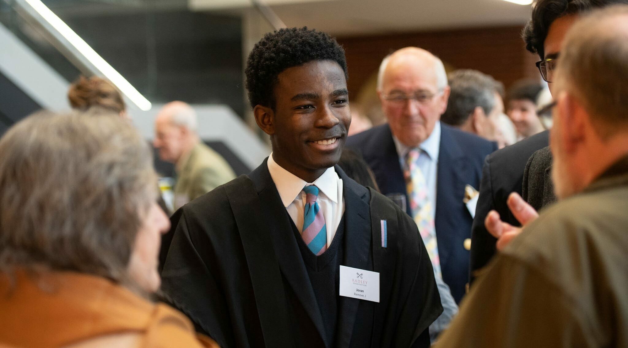 Boy smiling whilst speaking to people at an event.